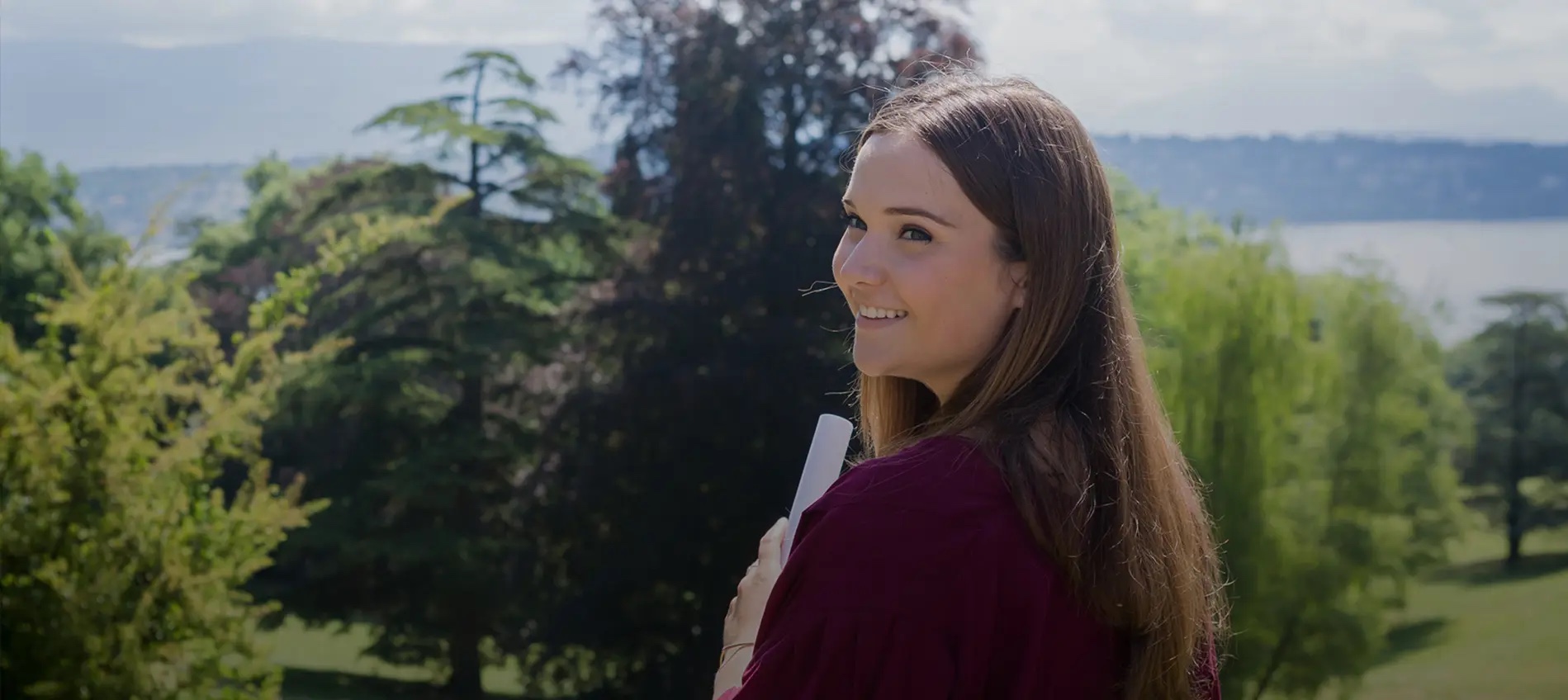 Geneva School of Diplomacy student smiling outdoors with Lake Geneva in the background
